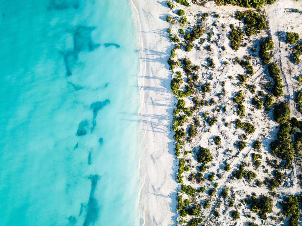 an aerial view of a beach and turquoise water.