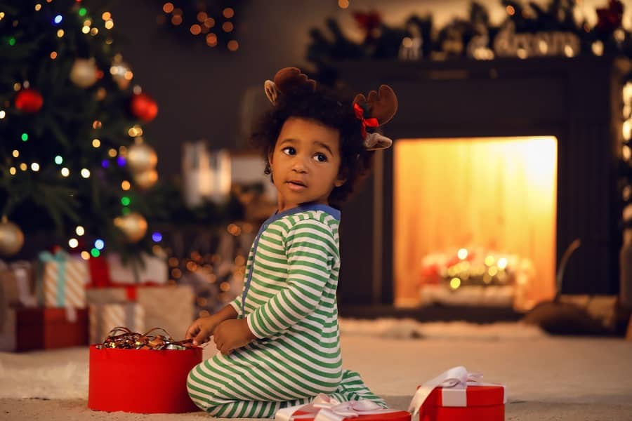 a little girl sitting in front of a christmas tree.