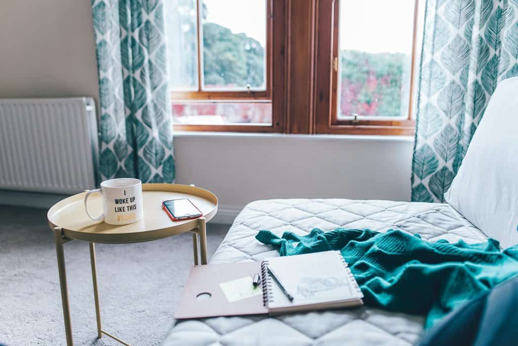 a room with a bed, a table and a laptop.