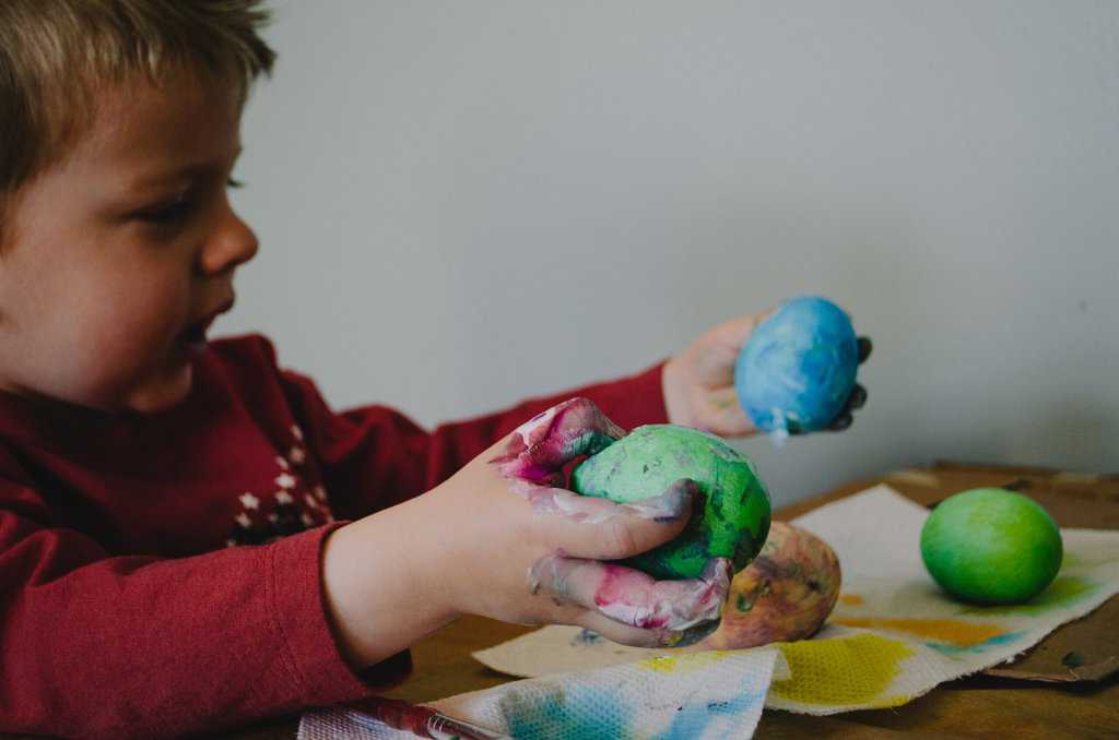 a young boy playing with paint on a table.