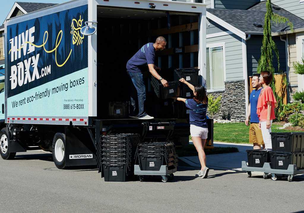 a group of people loading boxes into a moving truck.