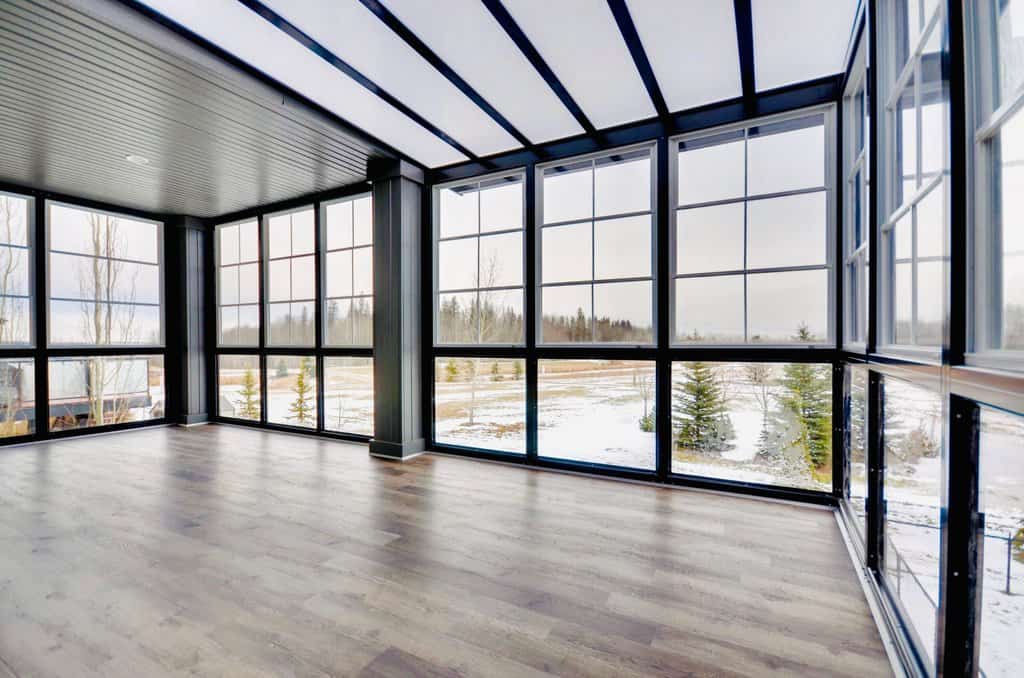 an empty room with large windows and wood floors.