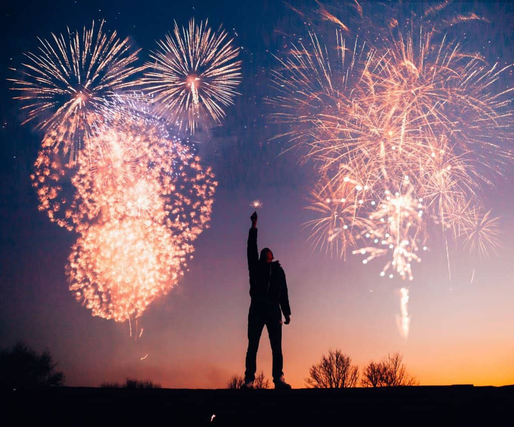 a man is standing on top of a hill watching fireworks.