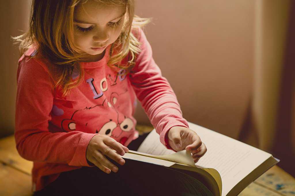 a little girl reading a book.
