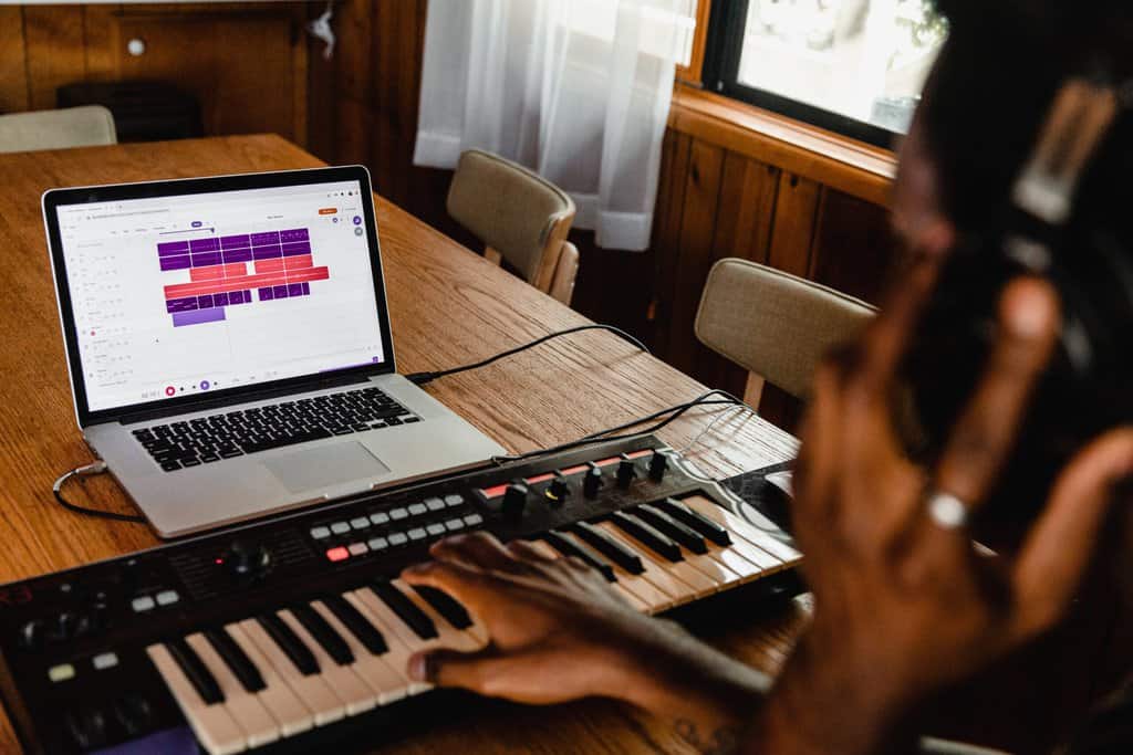a person playing music on a laptop at a table.