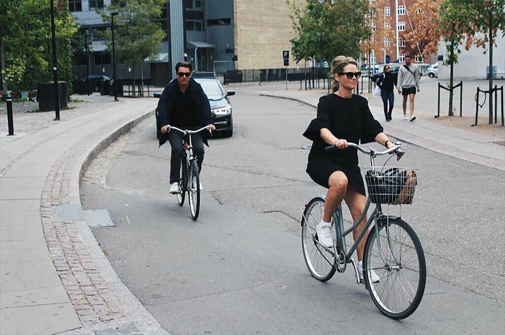 two people riding bicycles down a city street.
