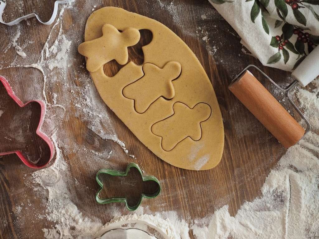 gingerbread cookie cutters and rolling pins on a wooden table.