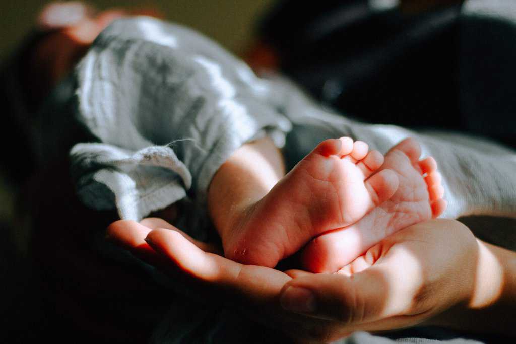 a person holding a baby's feet in their hands.