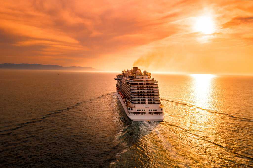 a cruise ship sailing in the ocean at sunset.