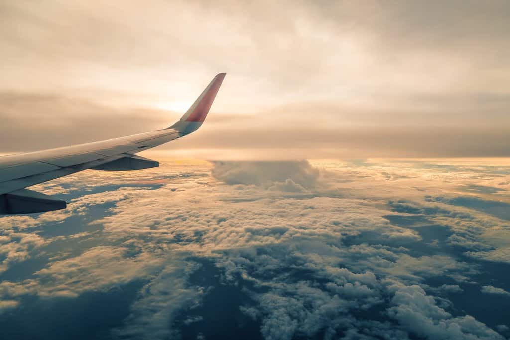 the wing of an airplane flying over the clouds.