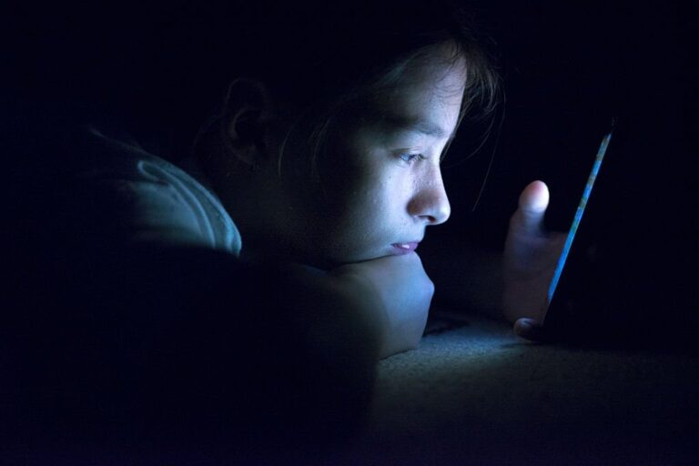 a young girl looking at her phone in the dark.