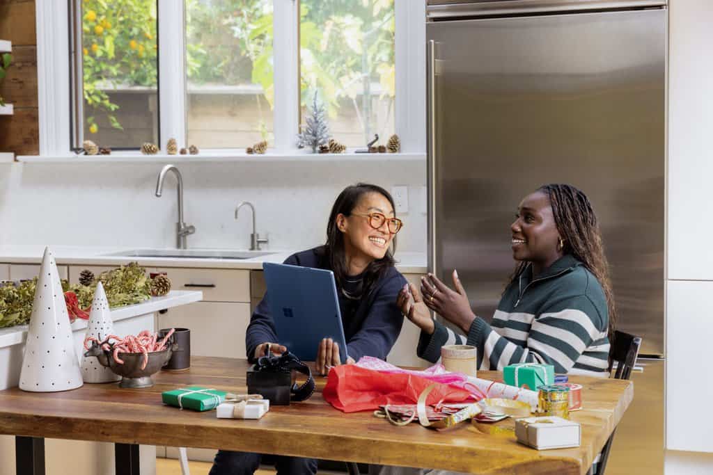 two women sitting at a table in a kitchen.