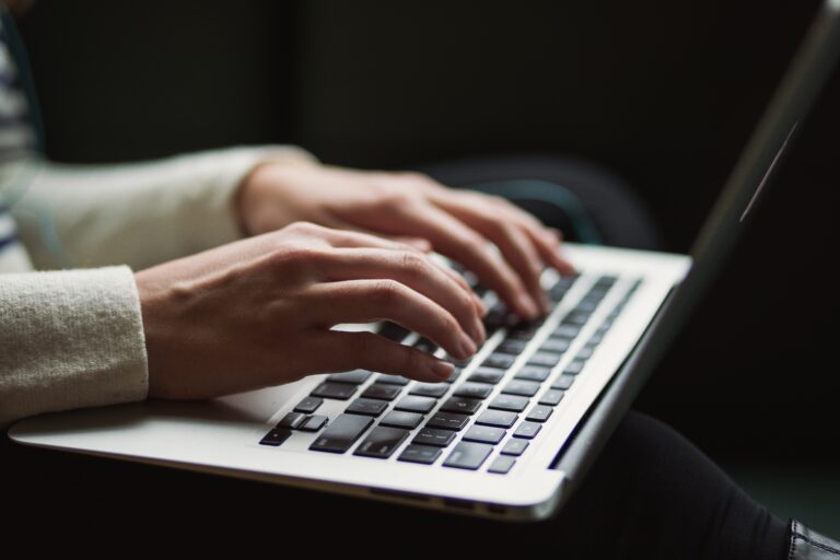 a woman's hands typing on a laptop.