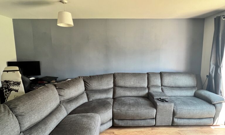 a grey sectional couch with a photowall in a living room.