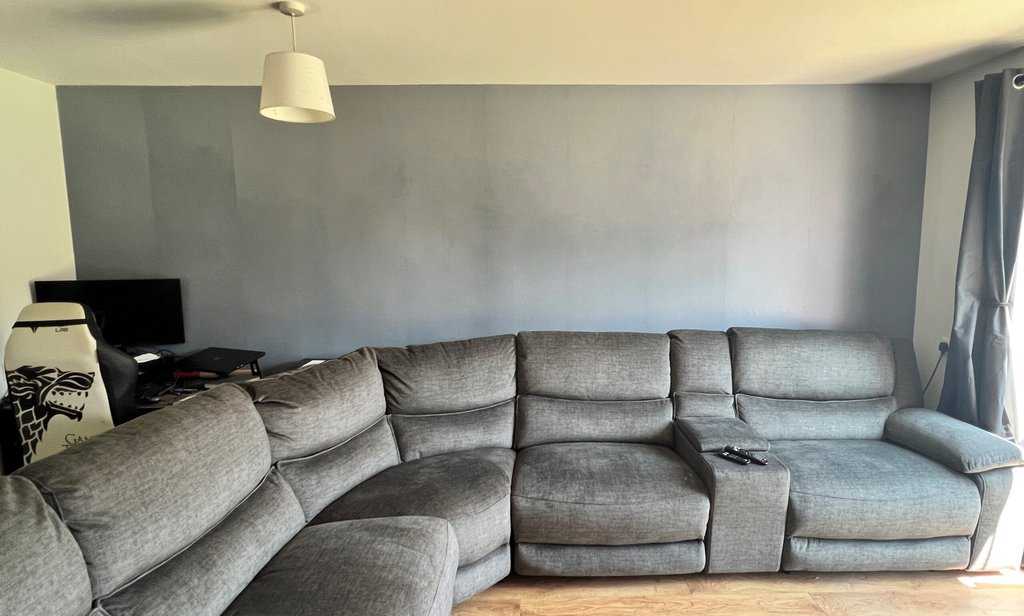 a grey sectional couch with a photowall in a living room.