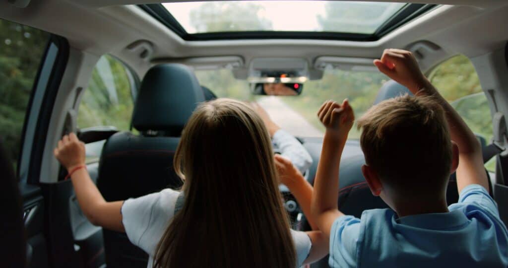 Two children are sitting in the back seat of a car.