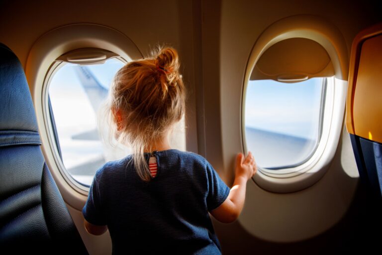 A little girl looking out the window of an airplane.