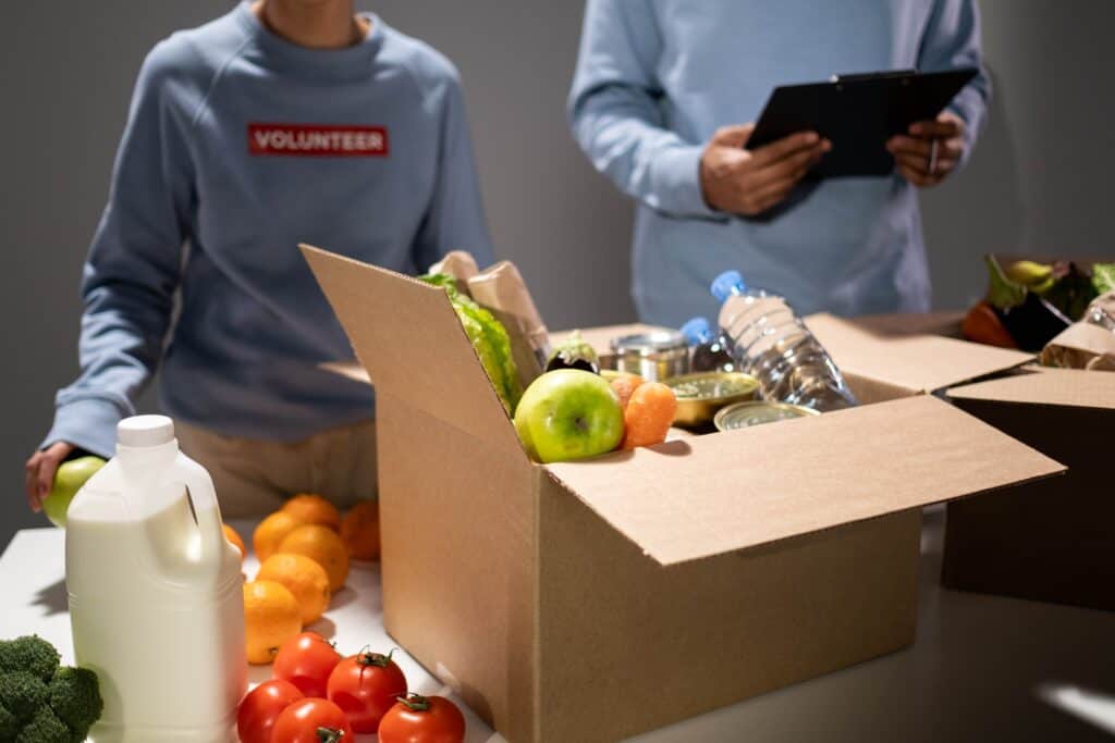 A man and woman standing next to a box of food.