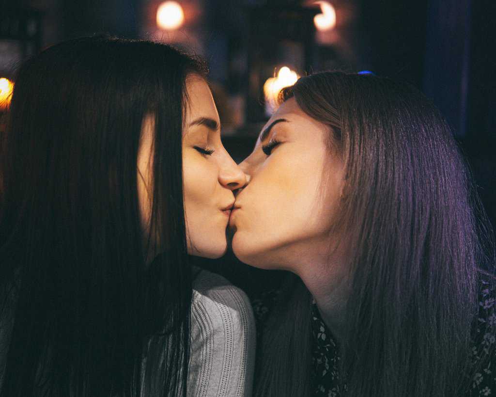 Two women kissing each other in a bar.
