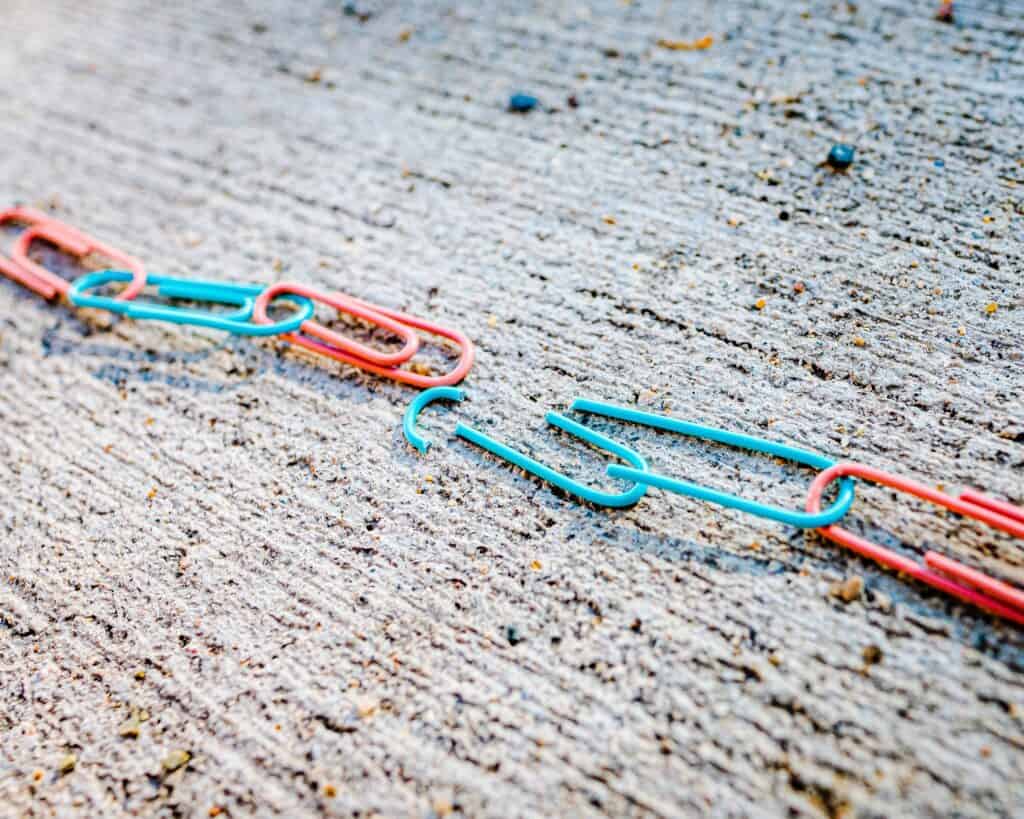 A red, blue, and green paper clip lying on the ground.