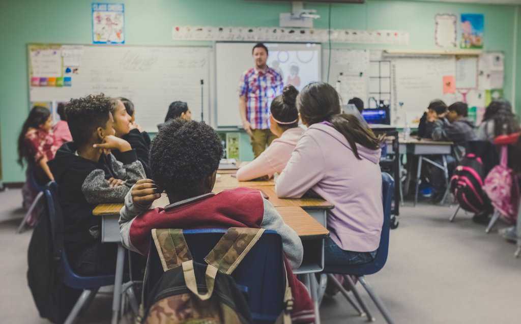 A group of students in a classroom learning from a presentation to successfully help them succeed.