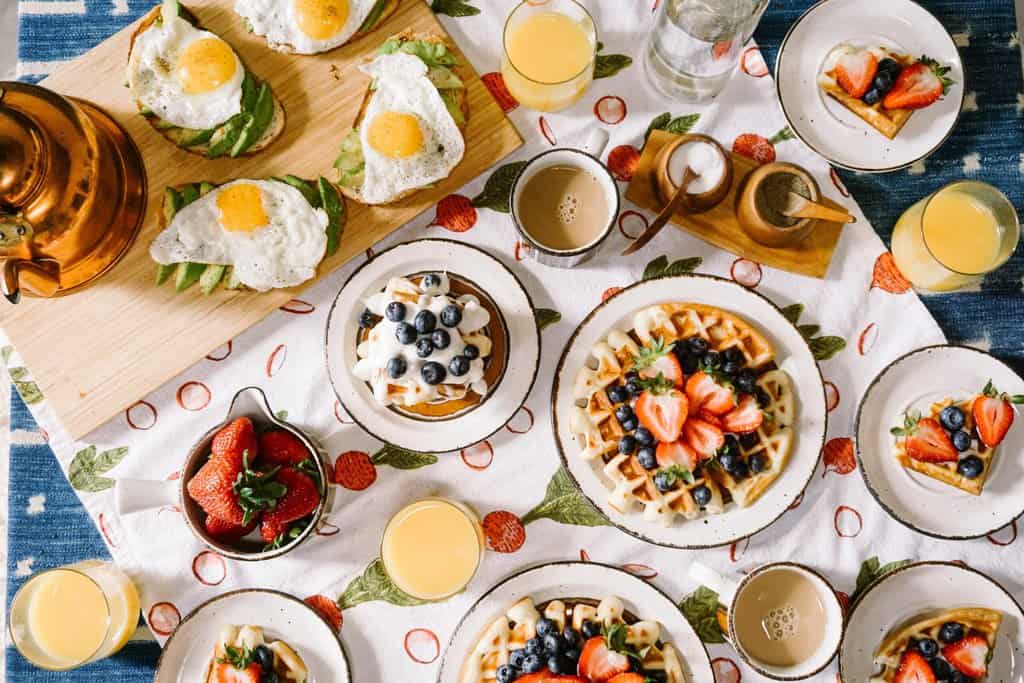 Nutritious waffles and eggs served with fresh fruit and juice on a vibrant tablecloth.