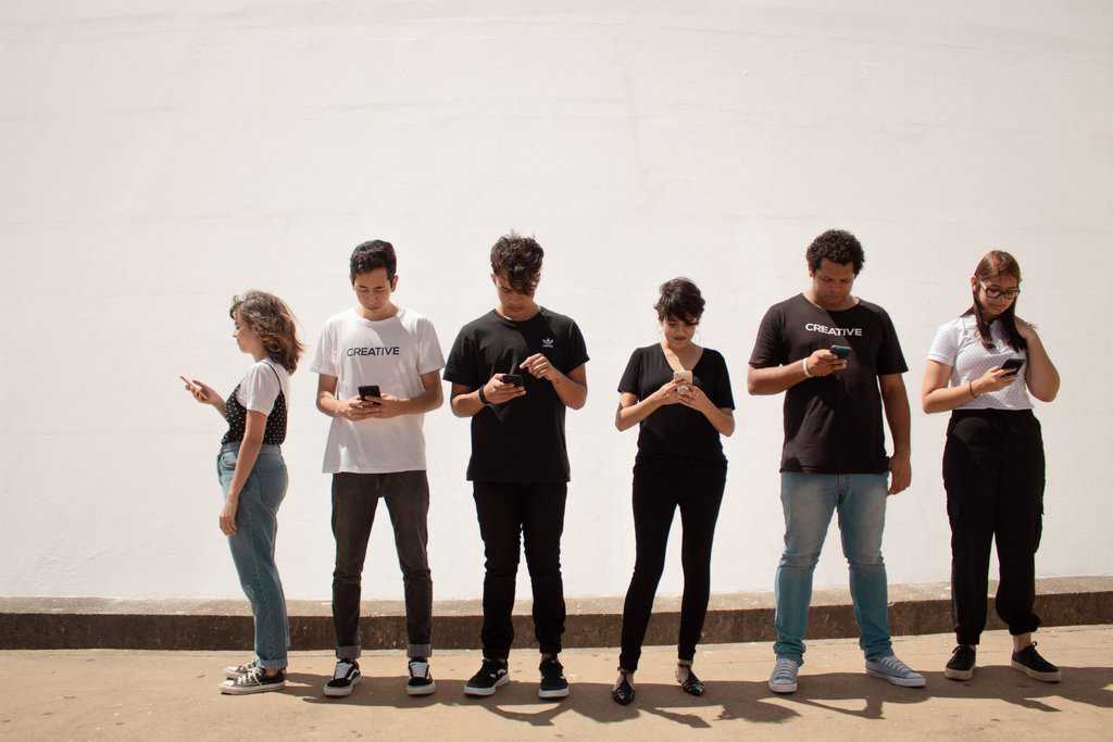 A group of trendy late teens standing in front of a white wall.