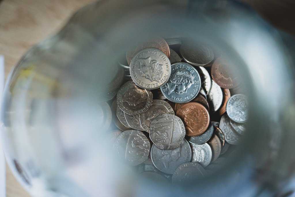 A jar full of coins on a table, showcasing budgeting tips while making your money go further during the holidays.